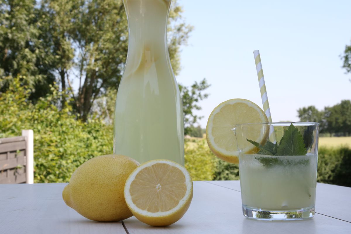 Selbst gemachte Zitronenlimonade in Flasche und Glas mit Strohhalm