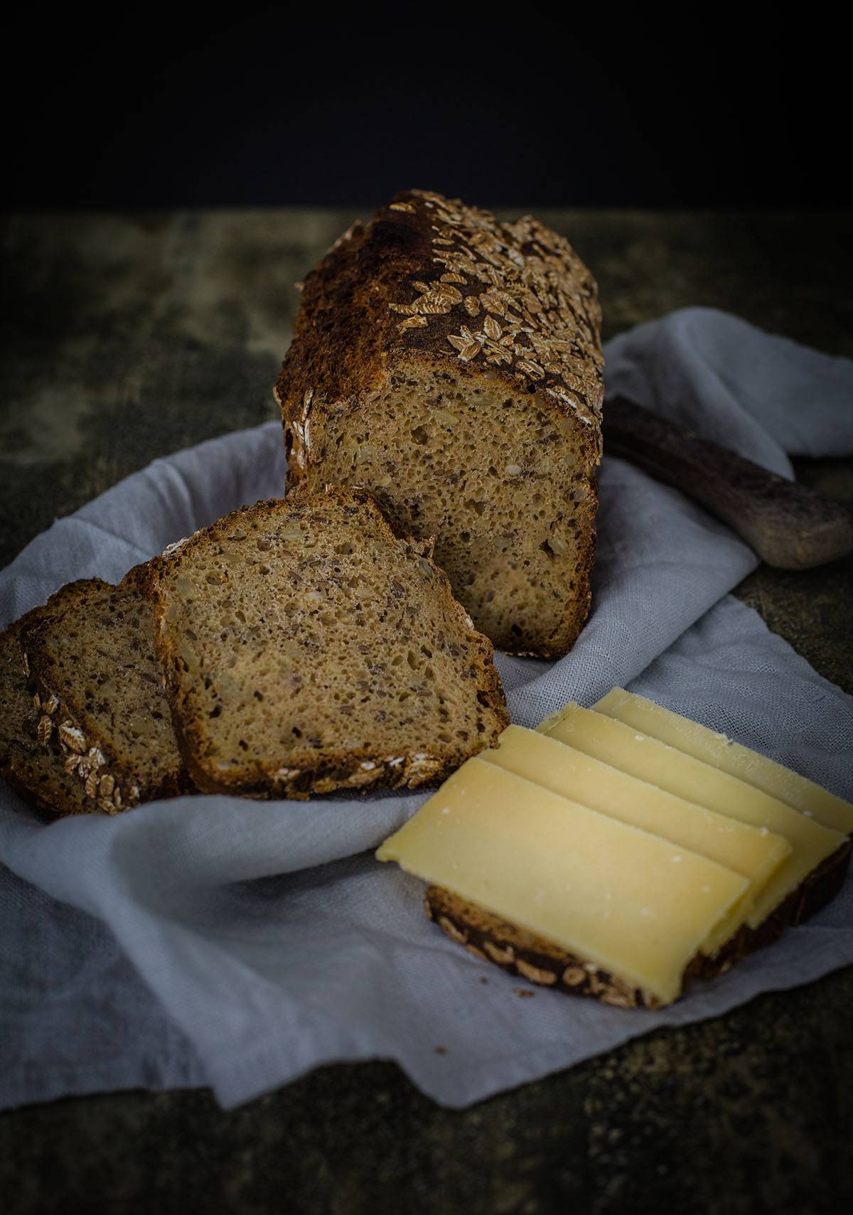 Angeschnittenes Dinkel-Vollkornbrot mit einer Scheibe Käsebrot