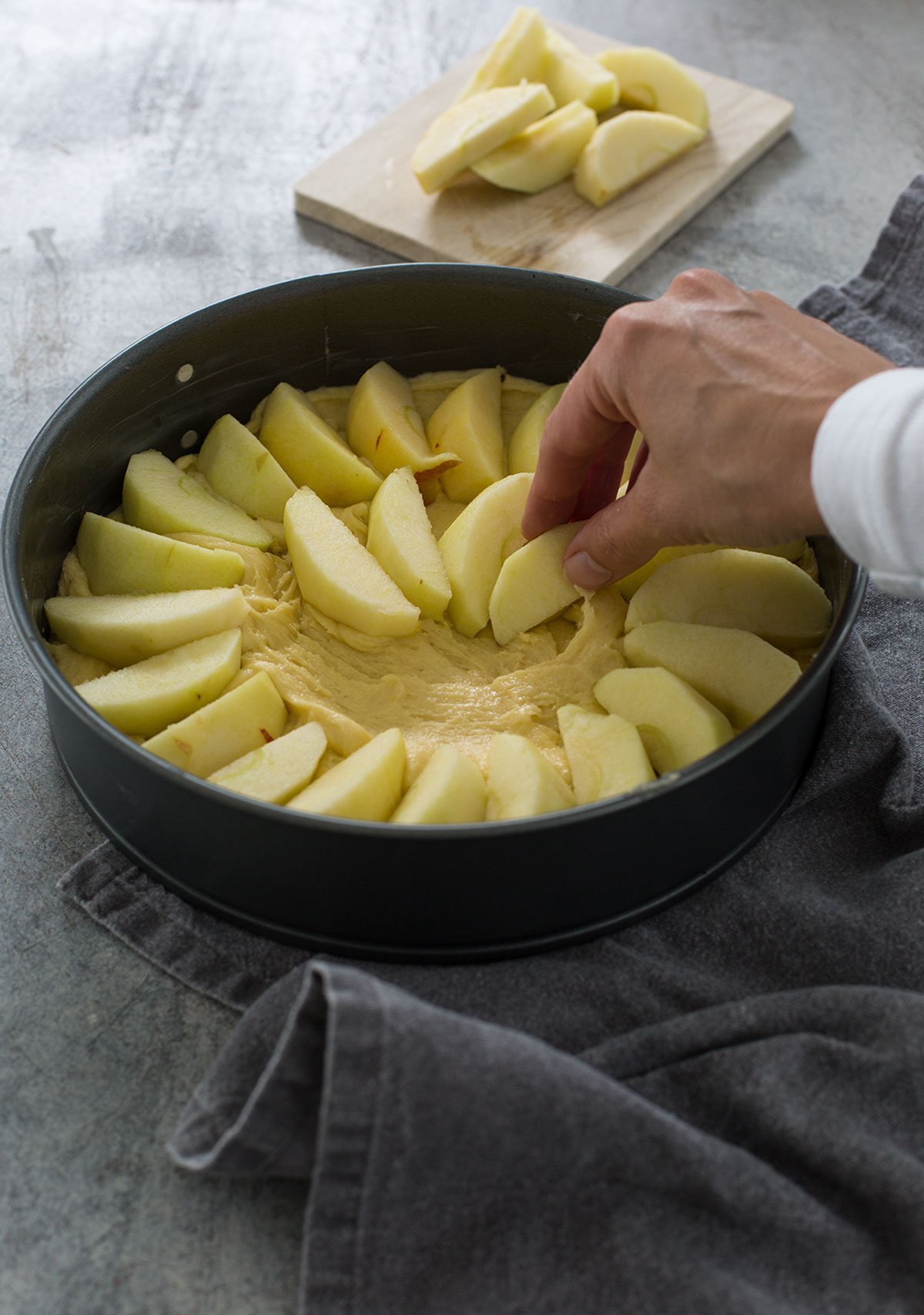 Äpfel auf Teig für Apfelkuchen legen