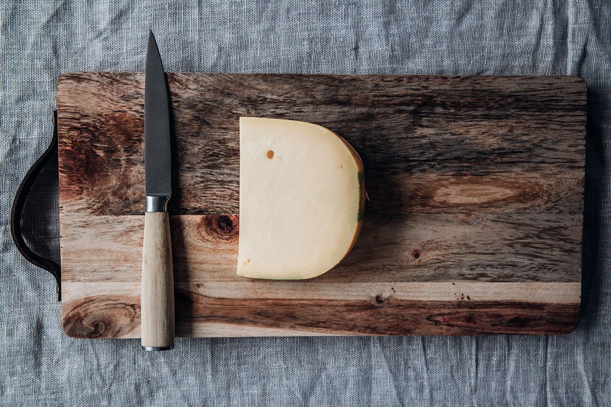 Großes Stück Käse auf Holzbrett mit Messer