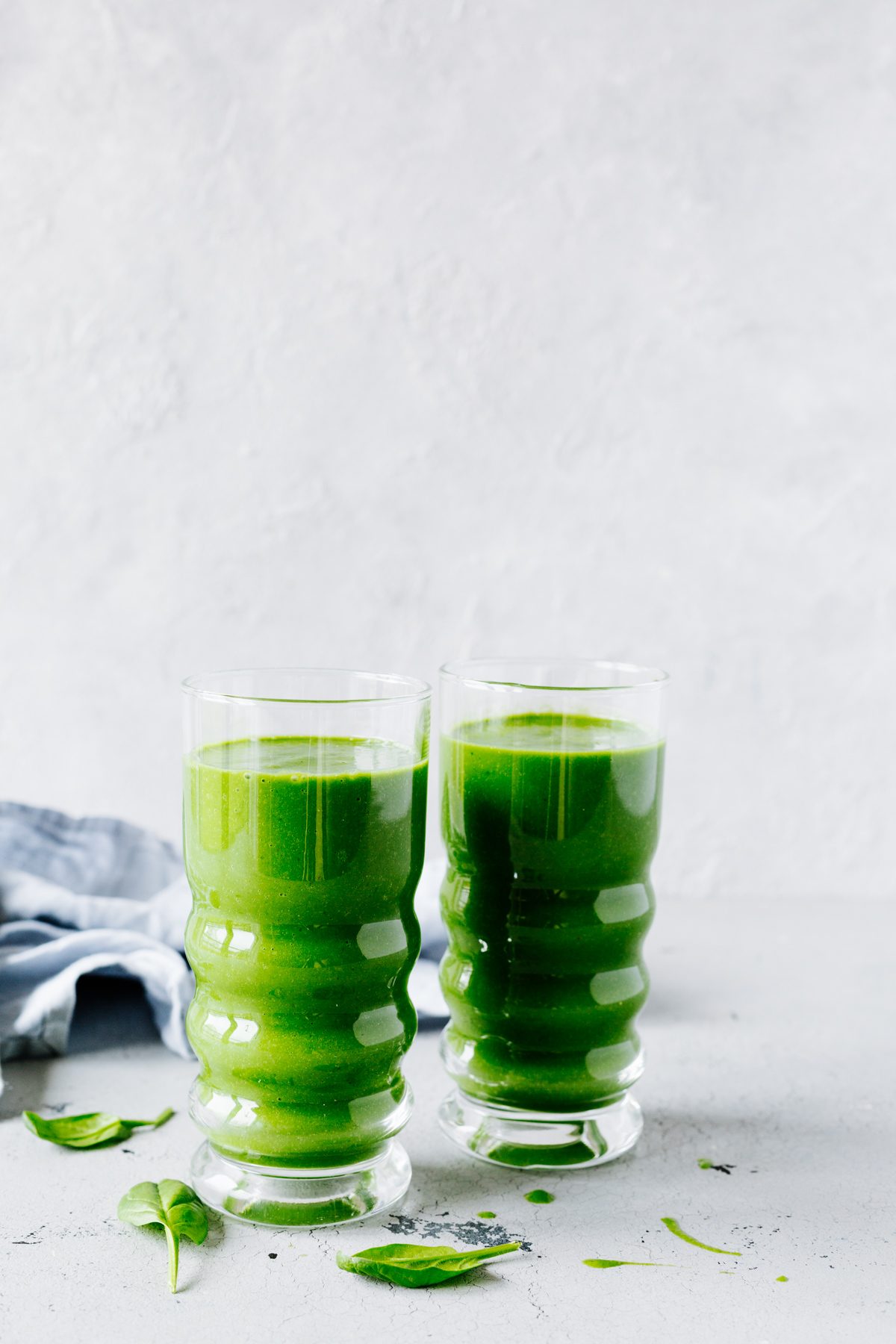 Grüner Smoothie mit Spinat in zwei Gläsern