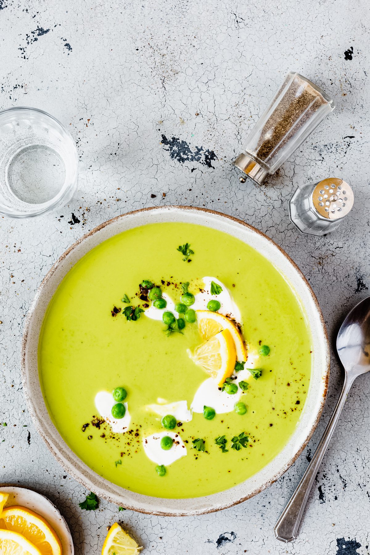 Grüne Erbsensuppe in Suppenschüssel mit Sahne, Zitrone und TK-Erbsen